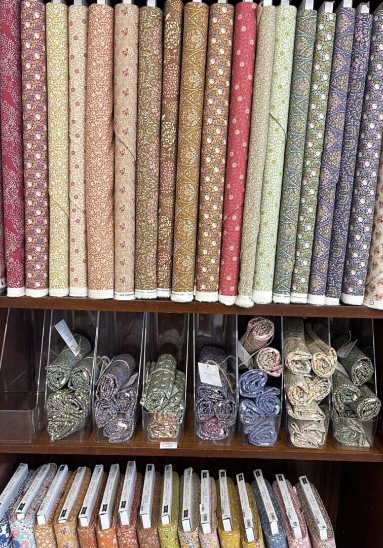 Colorful fabric rolls neatly arranged on shelves.