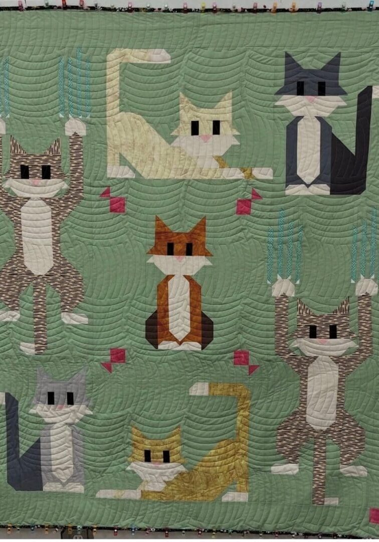 Green quilt featuring stylized cat blocks